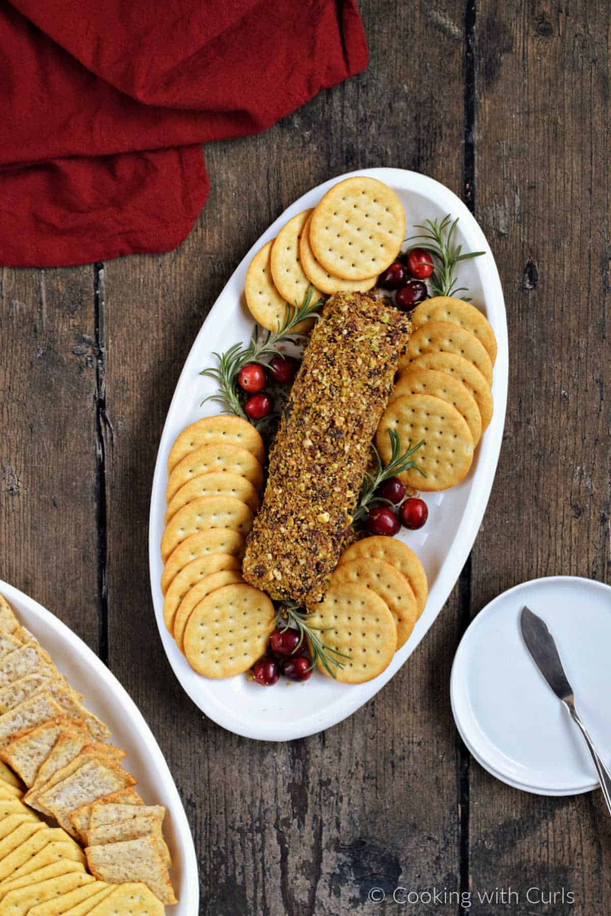 Cranberry pecan goat cheese log on an oval plate with crackers.