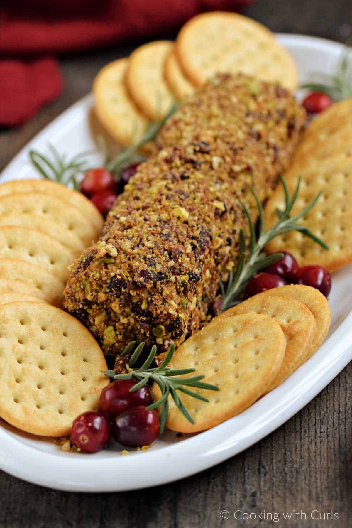 Cranberry pecan goat cheese log on a plate with assorted crackers.