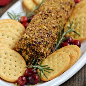 Cranberry pecan goat cheese log on a plate with assorted crackers.