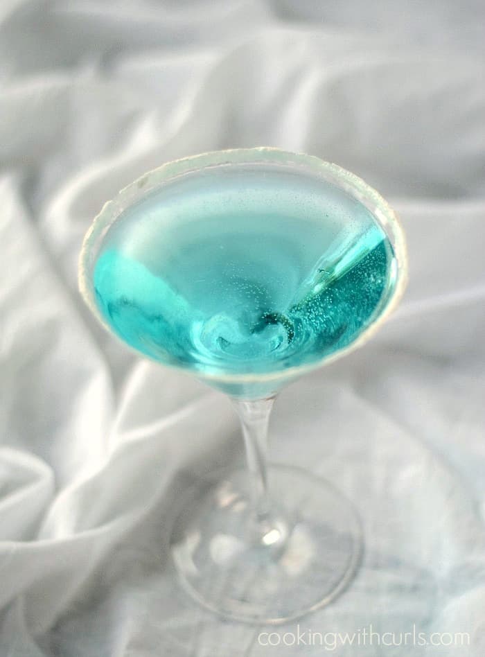 Clear blue martini in a martini glass with sugar coated rim.