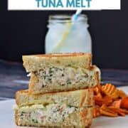Two halves of a tuna sandwich stacked on top of each other on brown paper with sweet potato chips and lemonade in the background and title graphic across the top.