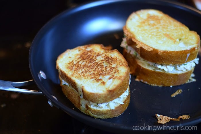 Two grilled tuna melts on sourdough bread in a non-stick skillet.
