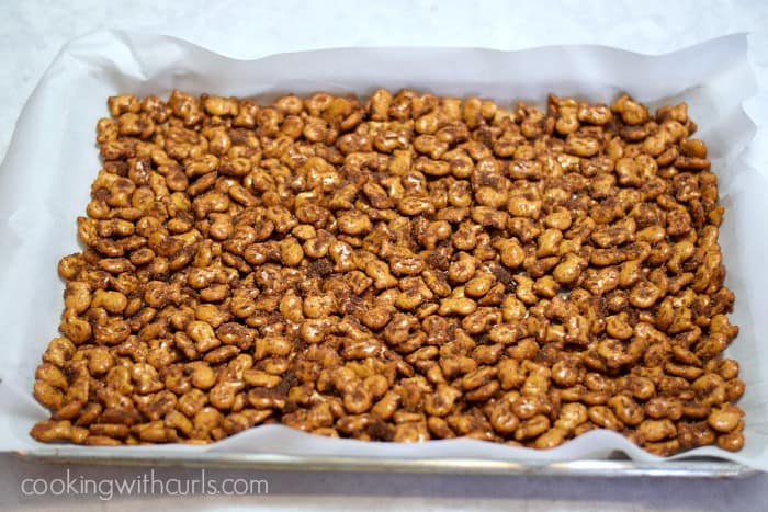 Cinnamon Sugar Goldfish pretzel mix spread out on a parchment lined baking sheet.