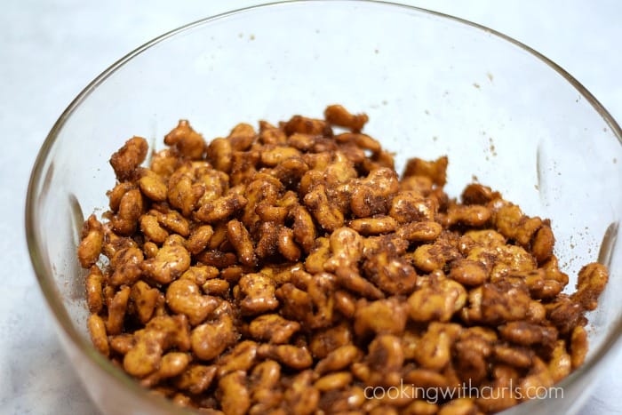 Goldfish pretzel crackers coated with the cinnamon sugar mixture in a large mixing bowl.