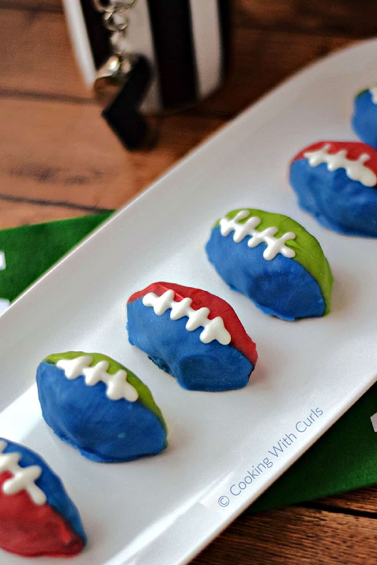Six OREO cookie balls shaped footballs on a rectangle serving platter. 