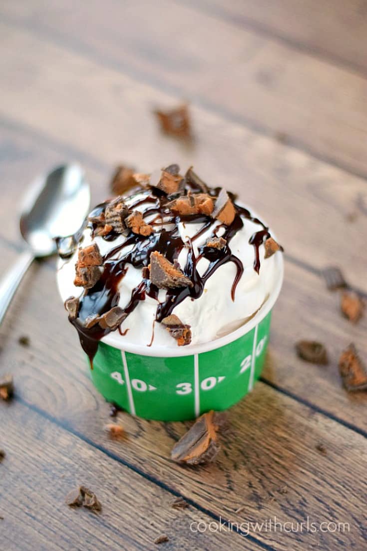 Touchdown Sundae Ice Cream Pie in a green football cup surrounded by broken Resse's peanut butter cups
