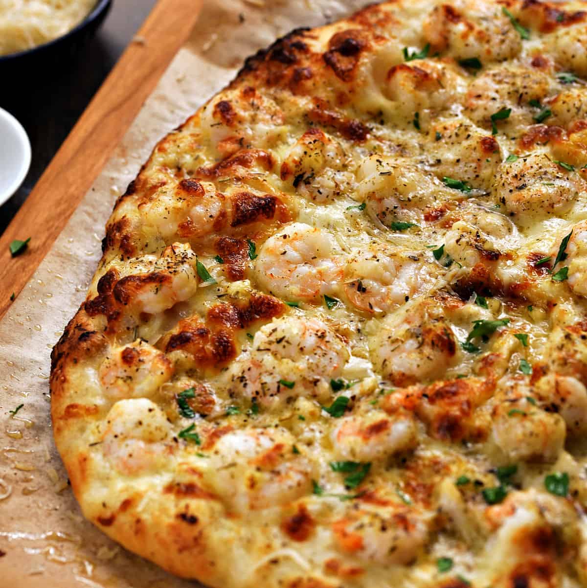 A whole shrimp scampi pizza topped with shrimp, melted cheese, and Italian parsley.