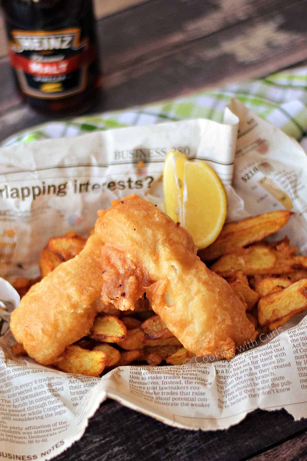 Beer Batter Fish on a bed of French fries in a newspaper lined basket.
