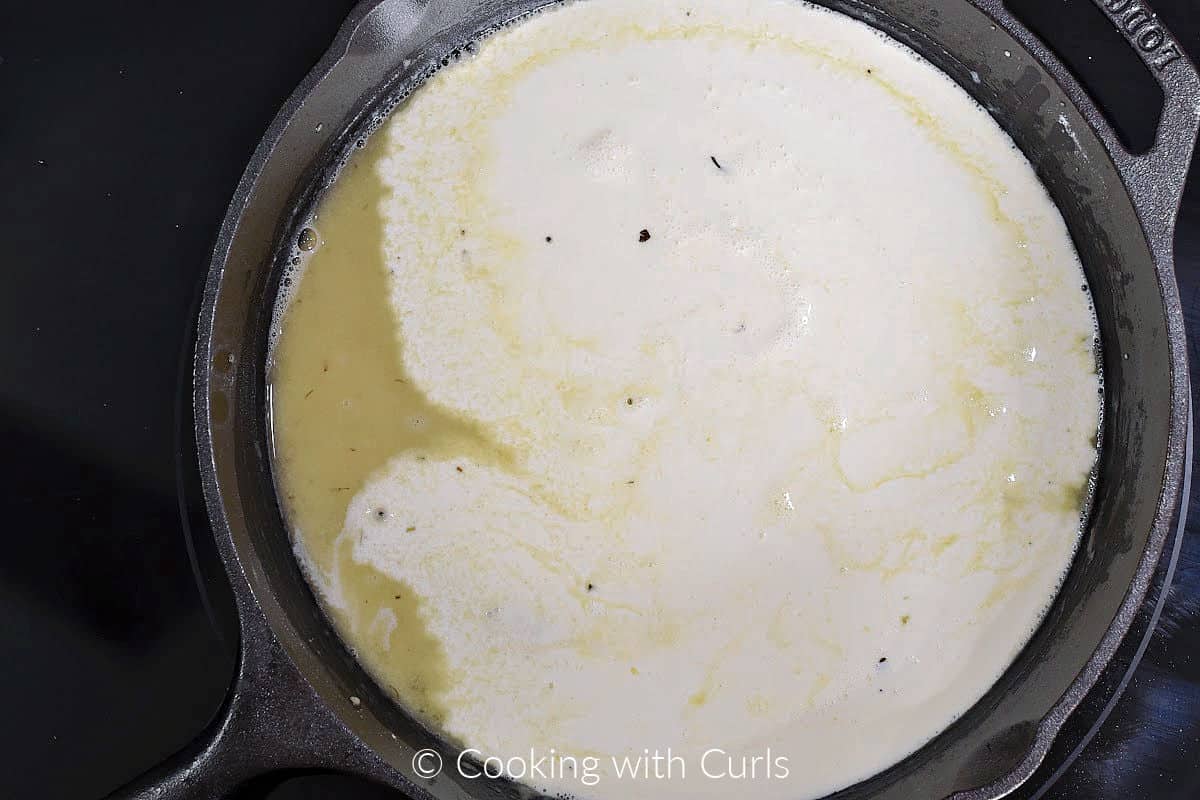 Chicken stock and cream added to a roux in a cast iron skillet. 