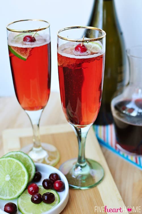 Two Cranberry Pomegranate Bellinis With Lime and cherry garnish.