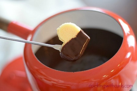 Dark Chocolate Cabernet Fondue in a red fondue pot with a heart shaped sliced of cake on a fork.