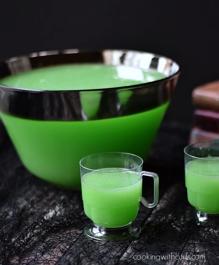 A punch bowl filled with green Polyjuice Potion with glasses of punch in front.