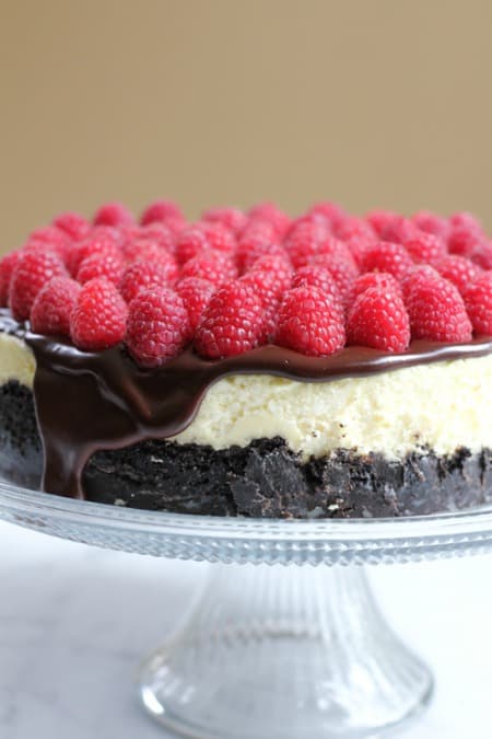 Raspberry-Cheesecake-with-Oreo-Crust on a glass cake stand.