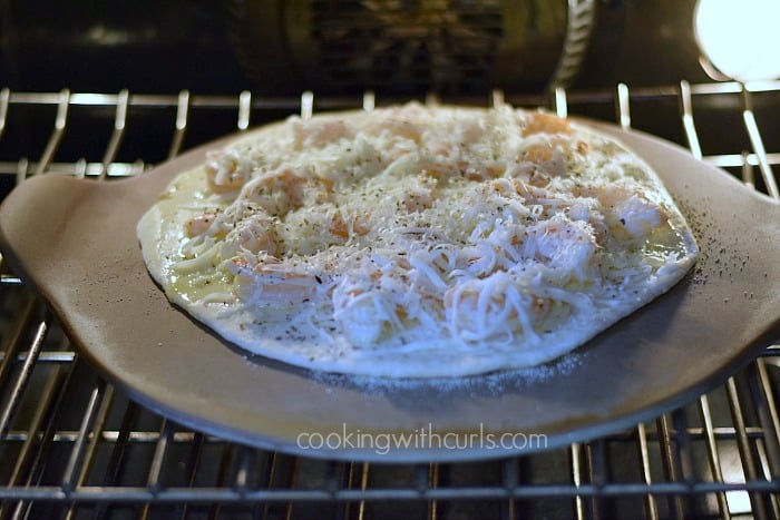 Shrimp Scampi Pizza on a pizza stone in the oven.