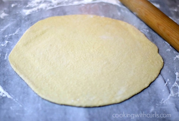 Pizza dough circle on a flour covered marble board.