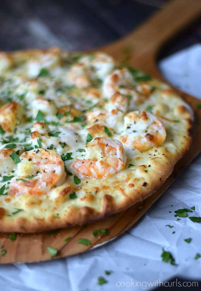 Shrimp Scampi Pizza topped with a light garlic-lemon sauce, and mozzarella cheese on a wooden pizza peel.