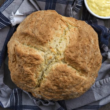 Looking down on a loaf of Traditional Irish Soda Bread with a bowl of butter on the side.