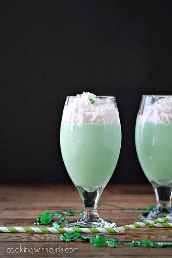 Two Boozy Shamrock Shakes topped with whipped cream.