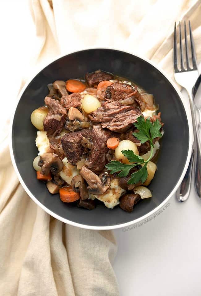 beef-bourguignon with mushrooms, carrots and onions in a black bowl.