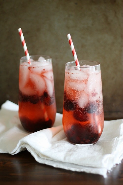 Two cherry sake cocktails with red and white striped straws.