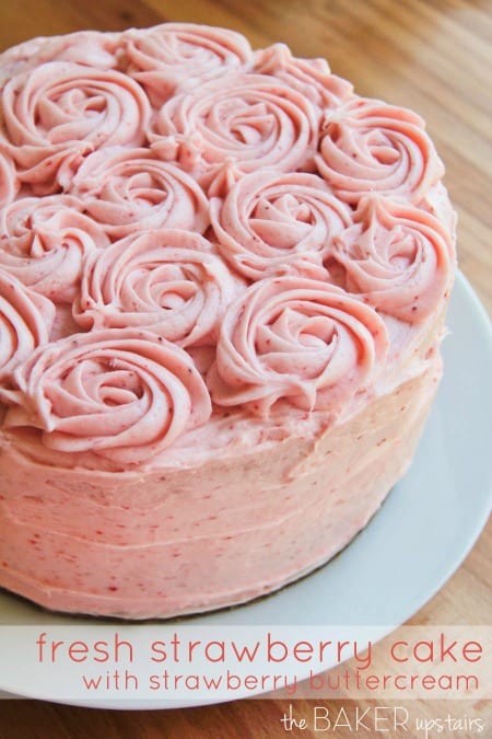 Fresh strawberry cake with decorative frosting roses on top.