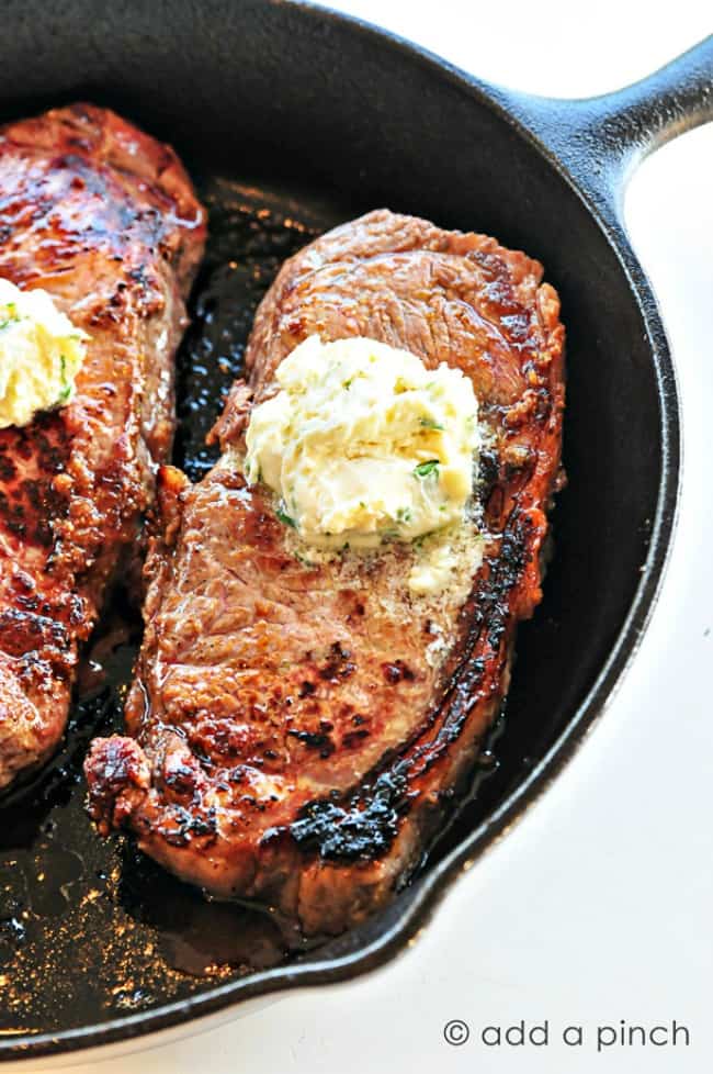 two skillet steaks with gorgonzola butter in a cat iron skillet.
