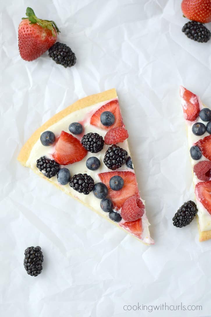 Two slices of a fresh blackberries, blueberries, strawberries and raspberries cookie pizza.