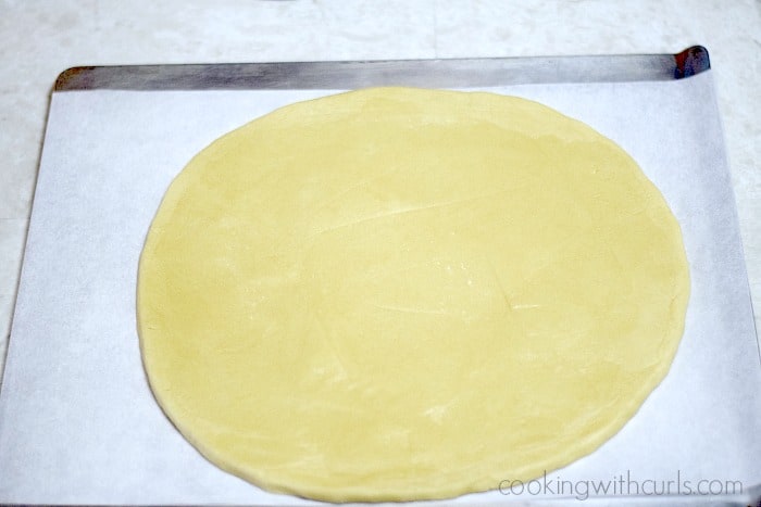 Giant cookie dough circle on a parchment lined baking sheet.
