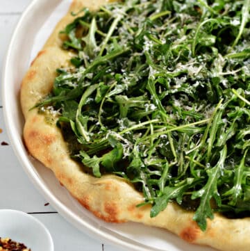 Greens Pizza Recipe with Italian crust, arugula, basil pesto, and grated parmesan cheese.