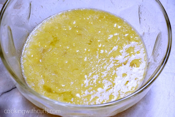 Mashed bananas, oil, milk, egg, and sugar mixed together in a large bowl.