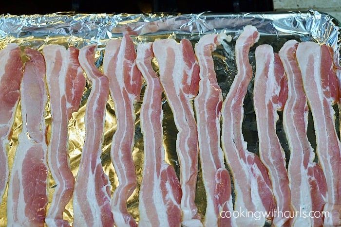 Raw bacon on a foil lined baking sheet.