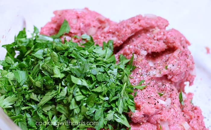 Ground meat and chopped parsley in a mixing bowl.