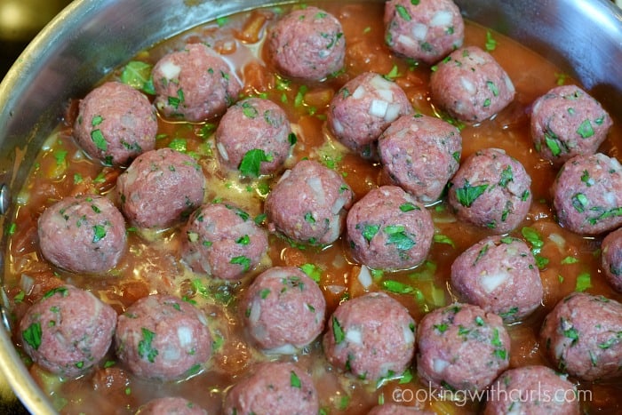 Raw meatballs added to the simmering tomato sauce.