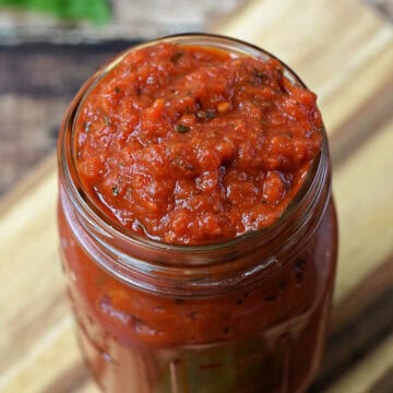 Classic Marinara Sauce in a glass jar sitting on a wood board.