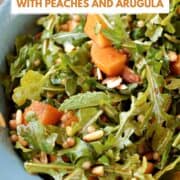 Arugula, couscous, peaches, and pine nuts salad in a serving dish with title graphic across the top.