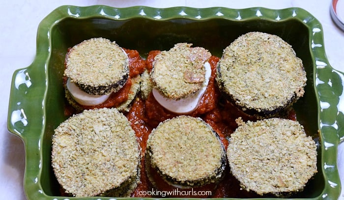 Six stacks of eggplant, sauce, and mozzarella cheese in a baking dish.