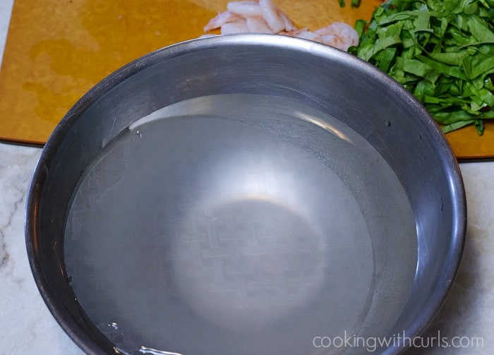 Rice paper wrappers soaking in a large bowl of water.