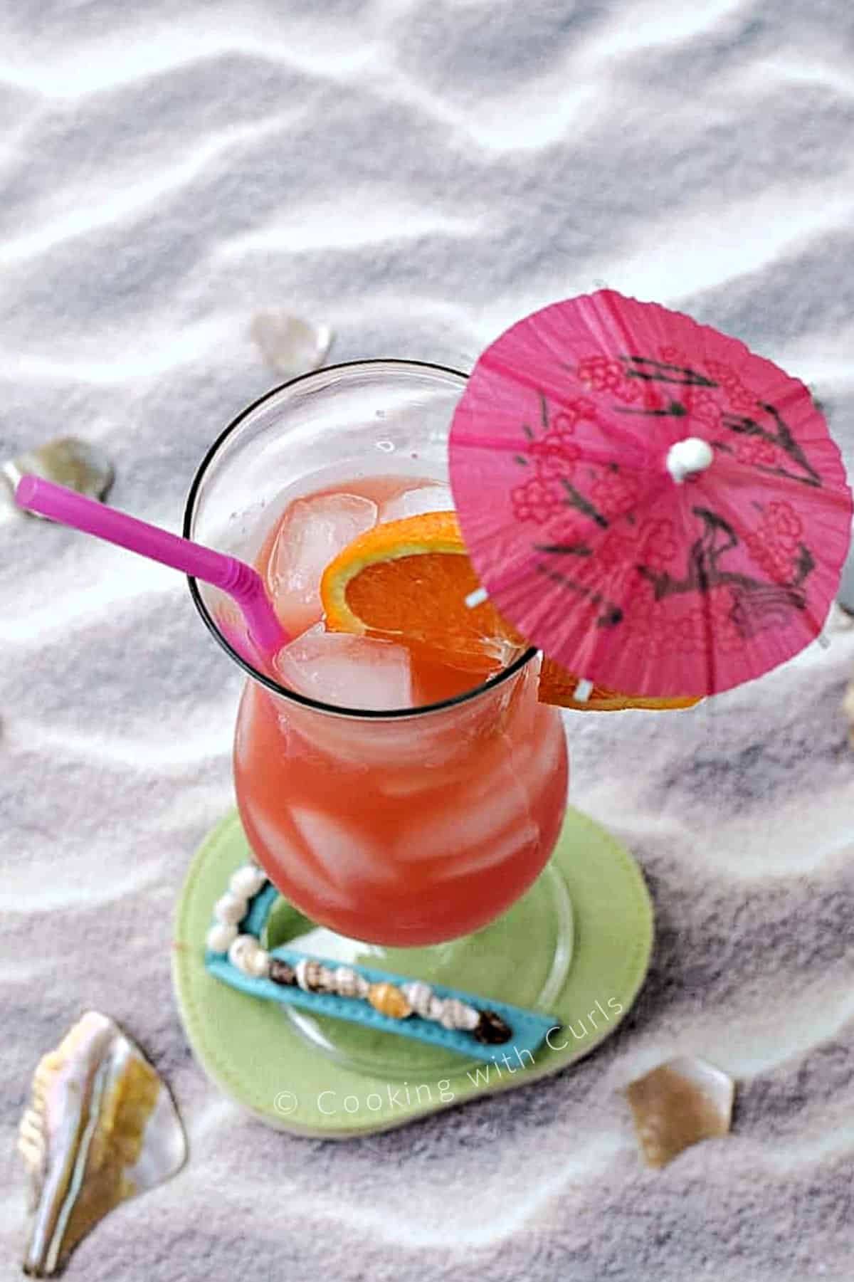 Bahama Mama drink on a flip flop shaped drink coaster sitting in the sand. 