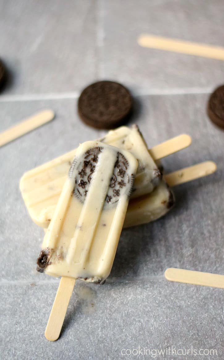 Three frozen Cookies and Cream Pudding Pops laying against each other on a tile background.