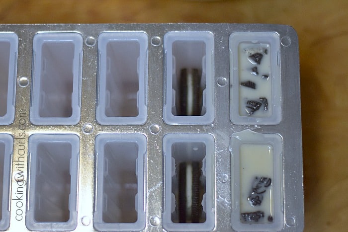 Whole oreo cookie placed in the bottom of two popsicle molds and two filled with mixture.