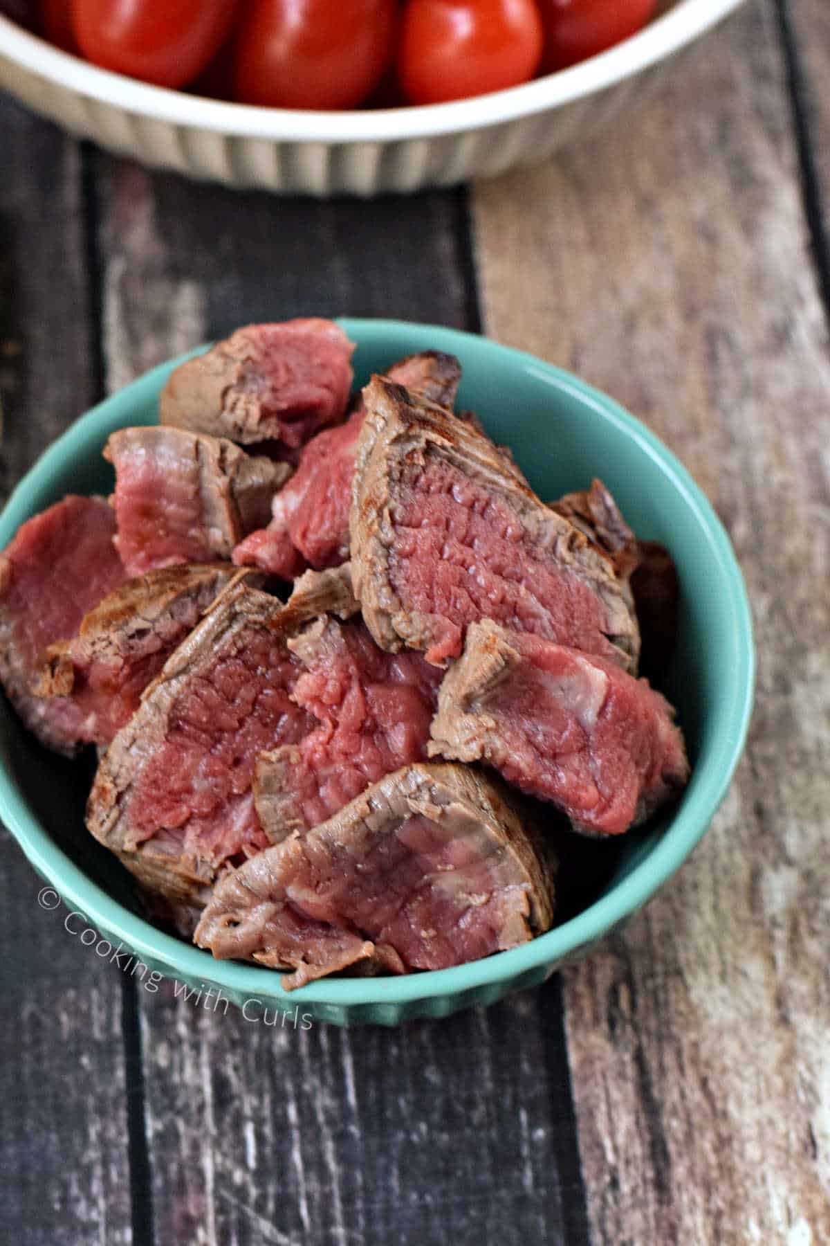 Medium-rare slices of steak in a small bowl.