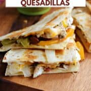Two chicken fajita quesadilla wedges stacked on a board with a bowl of salsa in the background and title graphic across the top.
