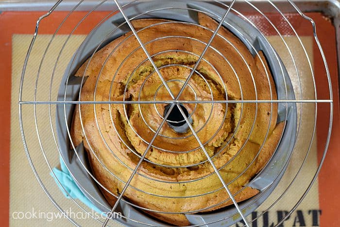 A round wire cooling rack resting on top of a baked bundt cake.