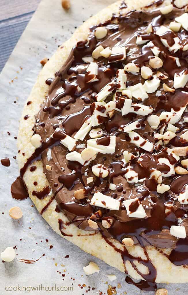Pizza topped with melted chocolate, white chocolate chunks, and hazelnuts.