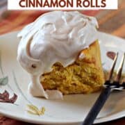 A pumpkin cinnamon roll topped with cream cheese frosting on a plate with a fork on the side with title graphic across the top.