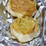Two bulbs of Roasted Garlic on foil.