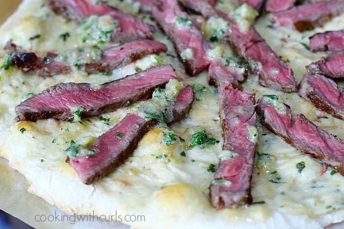 Baked pizza crust topped with thin strips of steak and drizzled with gorgonzola butter.