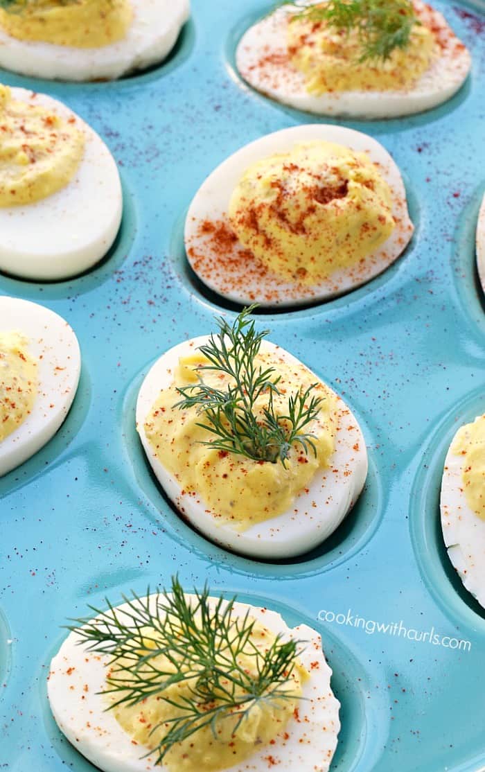 deviled eggs topped with dill leaves and paprika in a blue egg platter