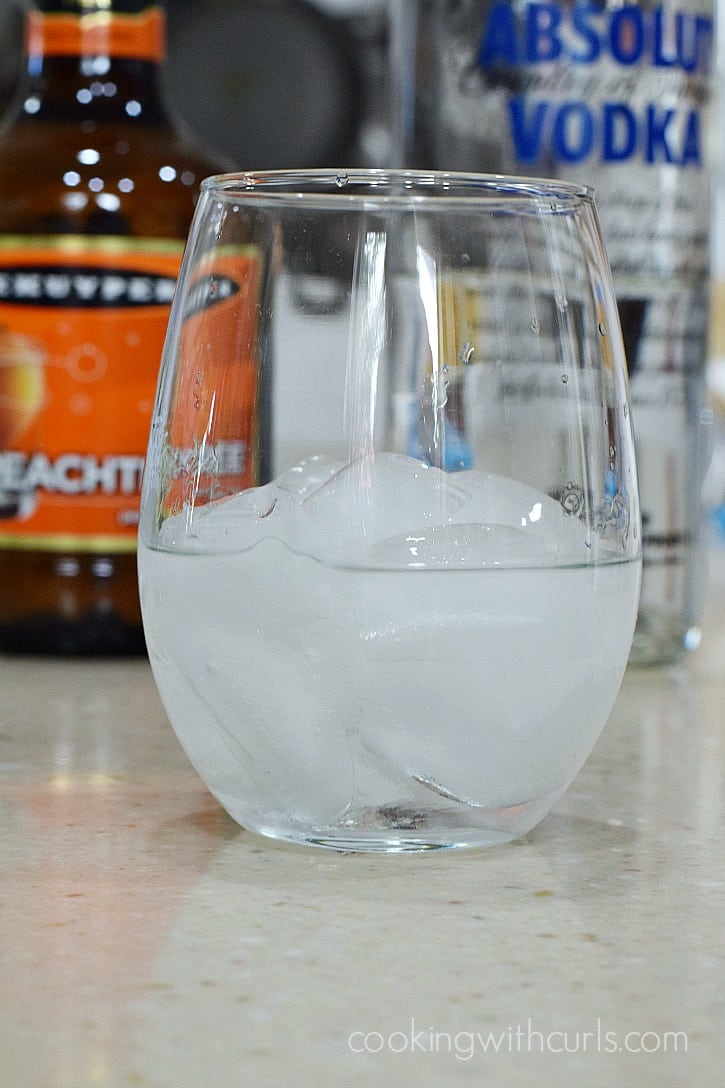 Peach schnapps, vodka, and coconut rum over ice in a small glass.