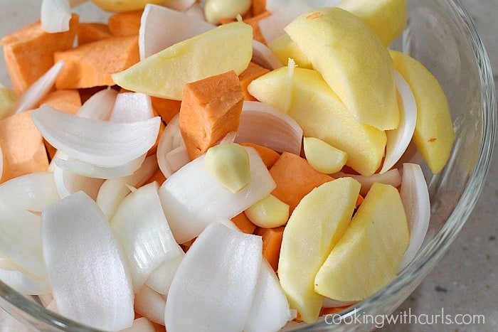 Chopped sweet potato, onion, apple, and garlic in a large bowl.
